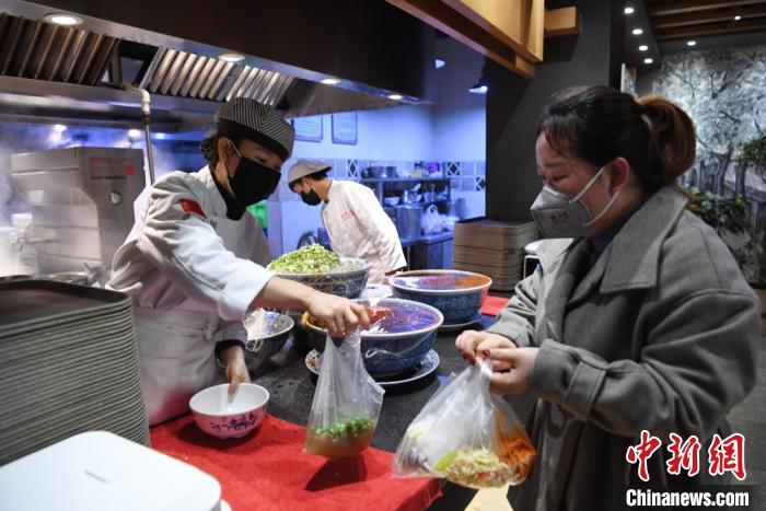资料图:日前返回兰州的务工人员,为食客打包牛肉面。 杨艳敏 摄 中国饭店协会:现金流成餐企最大问题,但未来可期